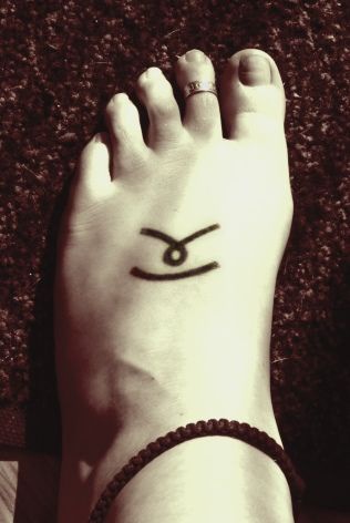 Symbole sur le pied,  tatouage en encre noire