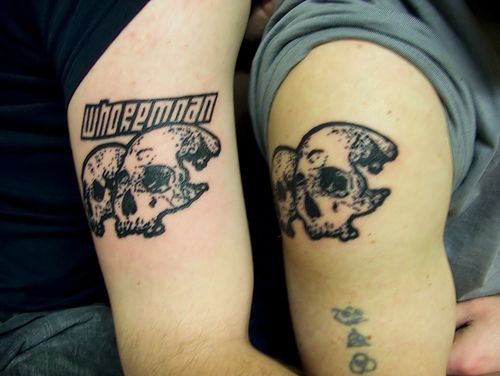 Similair skulls black ink tattoo