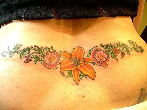 Tattoo mit wunderschönen farbigen Blumen an Zweigen am Becken
