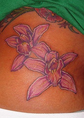el tatuaje de dos orquideas de color morado palido con blanco
