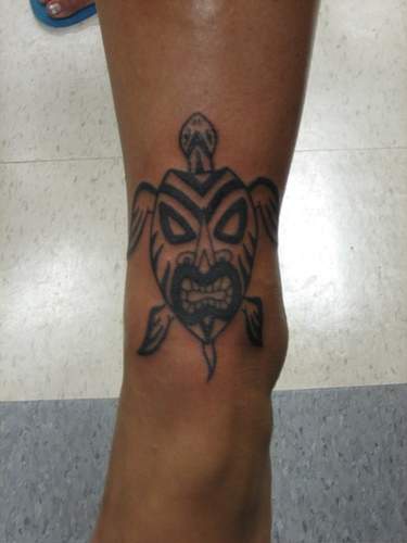 Tattoo of tribal turtle with angry mask on the shell