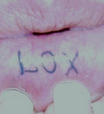 Tattoo on bottom lip, lox, short black word