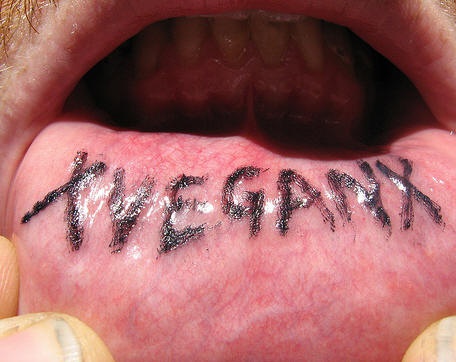 Tattoo mit stilisierter Inschrift &quotXveganx" in Schwarz an der Lippe