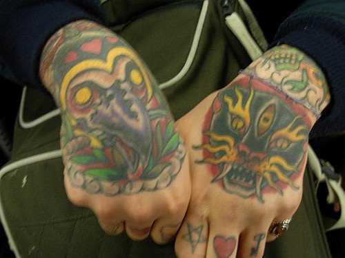 Tatuaje en la mano, pájaro y gato peligrosos