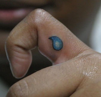 Tiny teardrop tattoo on finger