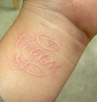 Tattoo in weißer Tinte mit Inschrift &quotVegan" am Handgelenk