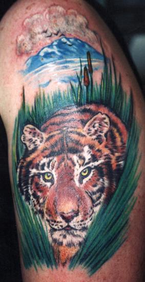 Tiger kriecht im Grün farbiges Tattoo
