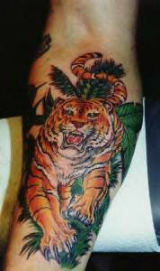 Tigre rugiendo entre las hojas verdes tatuaje en el brazo