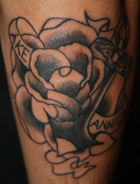 Traditional black ink tattoo with rose and stripe inscription