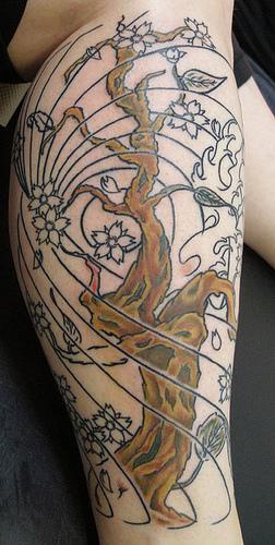 el tatuaje de pierna con una arbol con lineas largas y flores hecho en color