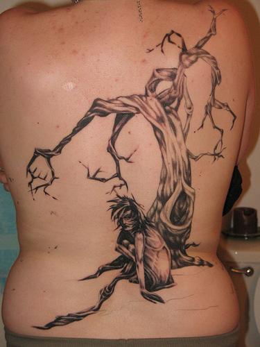 el tatuaje de un arbol viejo y un hombre hecho en tinta negra en la espalda