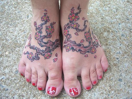 Tattoo mit Baum und bunten Blumen an Füßen