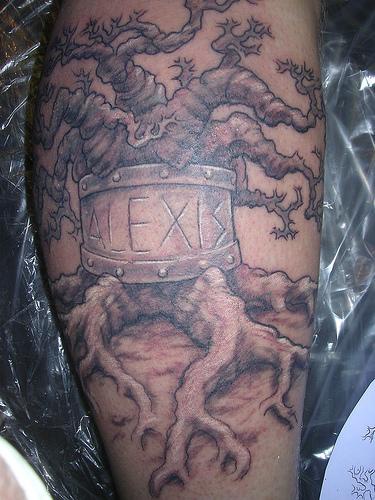 Tatuaggio impressionante l&quotalbero con la radice e la scritta attorno del tronco