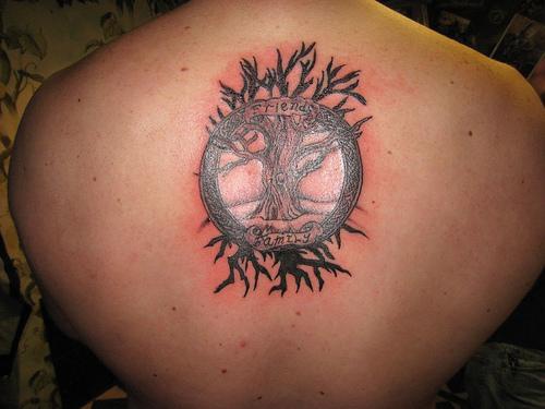 el tatuaje de un arbol viejo con un circulo en la espalda