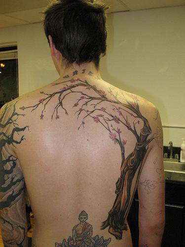 el tatuaje grande de buddha debajo de un arbol hecho en la espalda