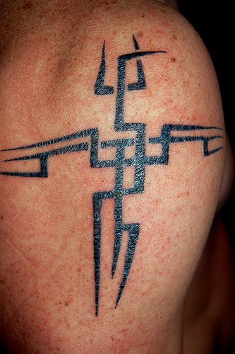 Tribal style cross tattoo on shoulder