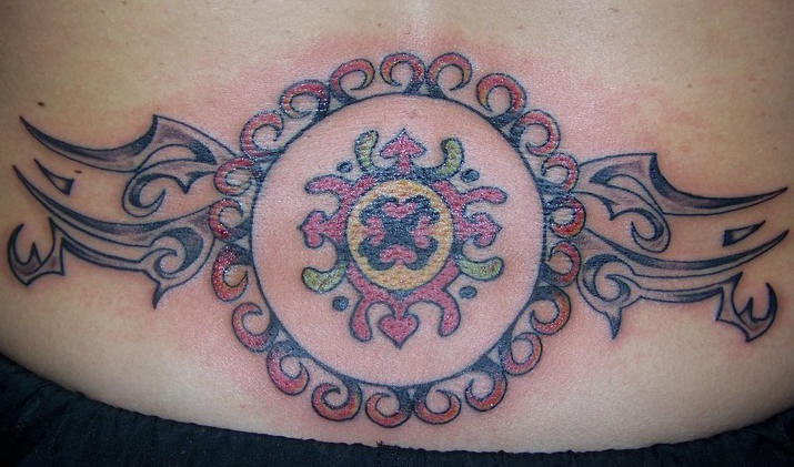 Un entrelacs cercle decoré et multicolore le tatouage tribal sur le bas du dos