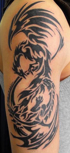 el tatuaje tribal de la ave fenix hecho en la tinta negra en el hombro