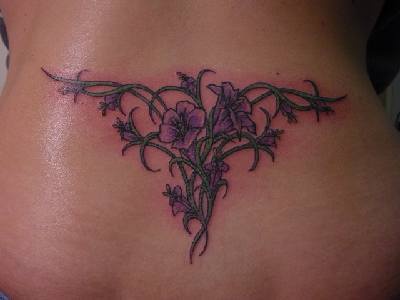 Simpático tatuaje estilo tribal con las flores en el bajo de la espalda