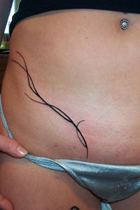 Tribal lower belly tattoo with long thin lines