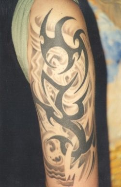 Gran tatuaje con los signos tribales en el brazo entero