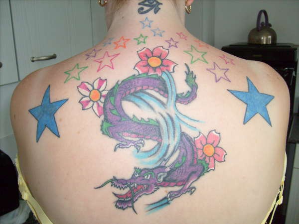 Tatuaje del dragón con flores y estrellas en color en la espalda