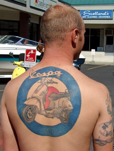 Tattoo mit Motorrad in blauem Kreis am oberen Rücken