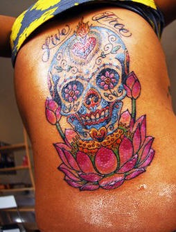 Le tatouage de haut du dos avec une crâne multicolore avec une inscription