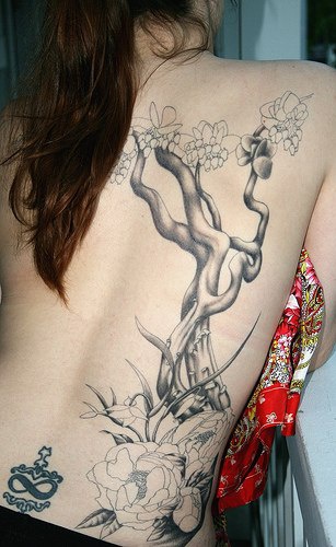 Schönes Tattoo mit Baum und Blumen am oberen Rücken