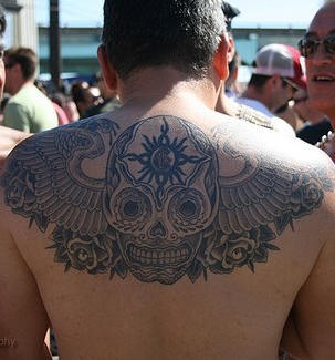 Verziertes Tattoo vom Schädel  mit Flügeln am oberen Rücken