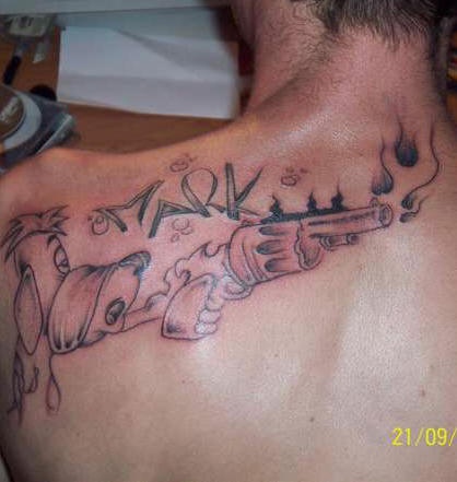 Dog    tattoo on upper back with a gun