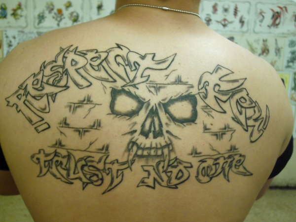 Le tatouage de haut du dos avec le visage de la crâne et une inscription