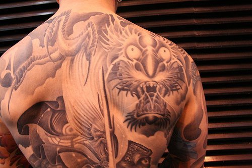 Gran tatuaje en la espalda dragón volando en el cielo