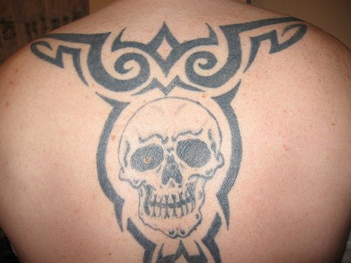 Tatuaggio sulla schiena il disegno in stile tribale & il teschio