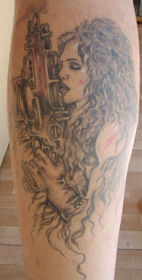 Tatuaje la mujer con pelo largo armada con la metralleta