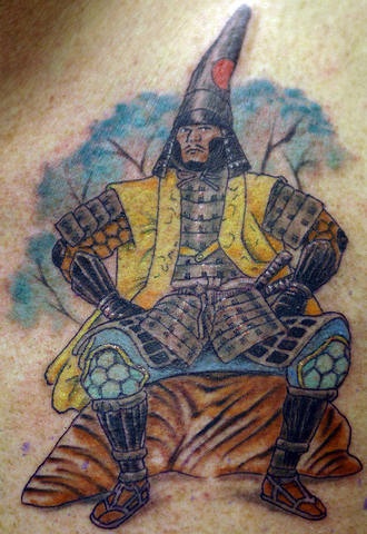 Tatuaje en colorn guerrero  japonés sentado en la piedra