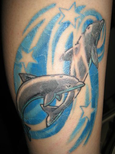 Two dolphins in blue waves decorated with stars tattoo