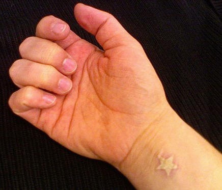 White ink wrist tattoo with small star