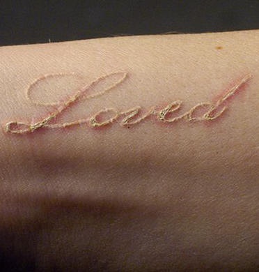 Tatuaje en tinta blanca con la inscripción &quotLoved"