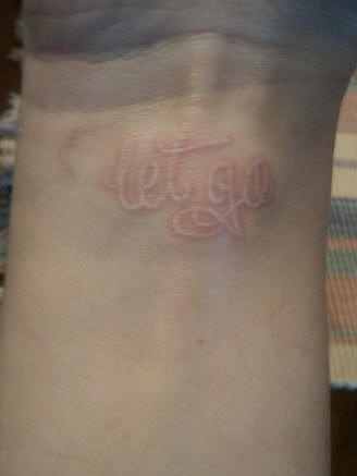 Tatuaje en tinta blanca la inscripción &quotLet  go" en la muñeca