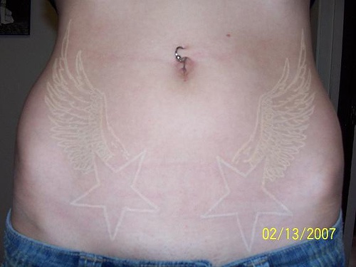 White ink tattoo with wings and stars on belly