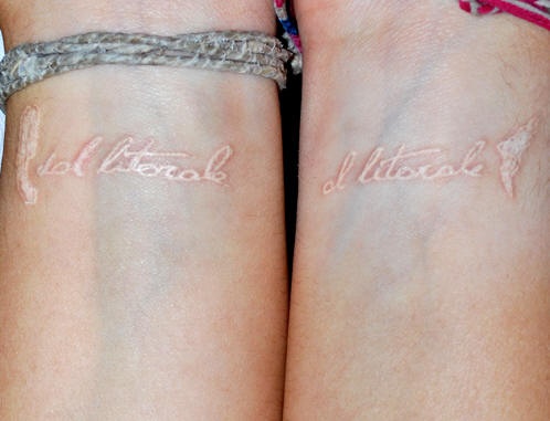 White ink inscription tattoo on wrist
