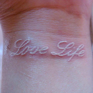 White ink wrist tattoo with inscription love life