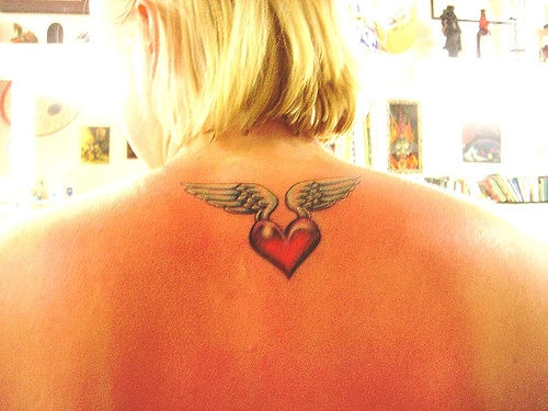 Kleine Flügel Tattoo mit rotem Herzen auf Nacken