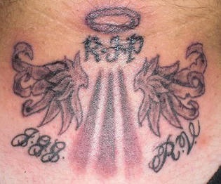 el tatuaje conmemorativo &quotdescansa en paz" con alas y los rayos