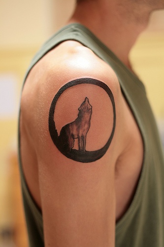 Tattoo mit heulendem Wolf in einem Kreis