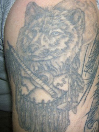 Tatuaggio pittoresco sul braccio la testa del lupo con oggetti tribale