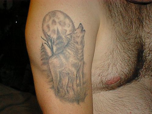 Tattoo on shoulder with howling wolf on the moon