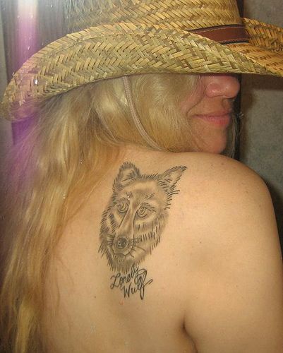 Tattoo mit Wolfskopf und Unterschrift am Schulterblatt