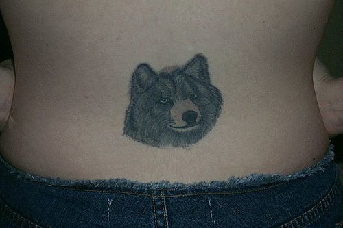 One wolf head tattoo on low back